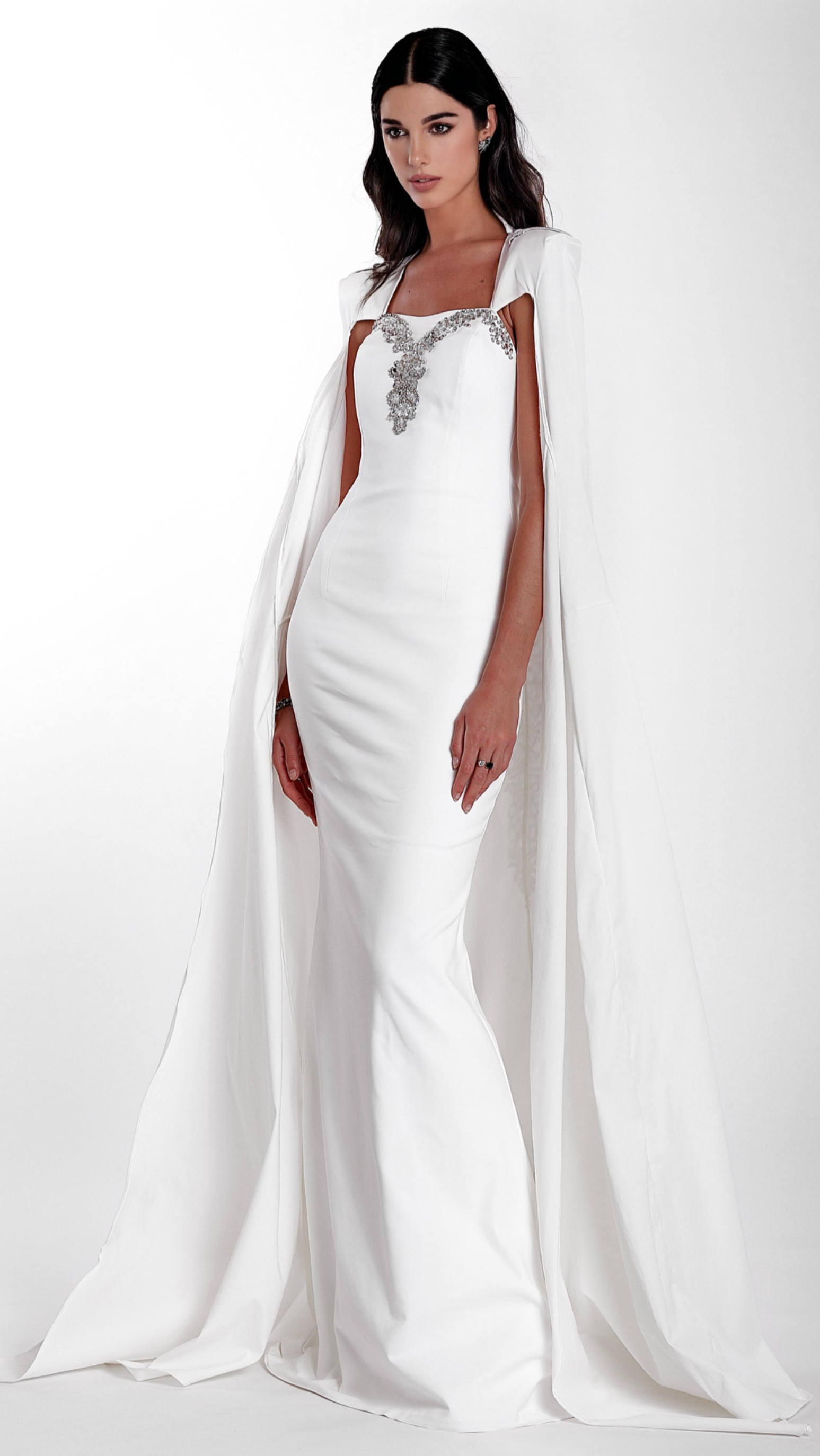 La robe longue Lampétie avec sa cape Circé en blanc sont brodées à la main.

Robe :

Bustier col-cœur couvrant l’intégralité de la poitrine en la rehaussant et en épousant ses formes.
Sans bretelles ni armatures.
Arabesques de perles et sequins dessinant le cœur de la poitrine.
Fermeture zippée invisible au dos de 32 cm.
Fente au milieu du bas du dos de la robe qui couvre les chaussures.
Coupe ajustée affinant la taille.Soie naturelle d’un fini mat opaque.
Confectionnée en taille standard ou en sur-mesur